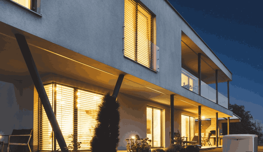 A home with lights on during a nighttime storm, powered by a Generac backup generator